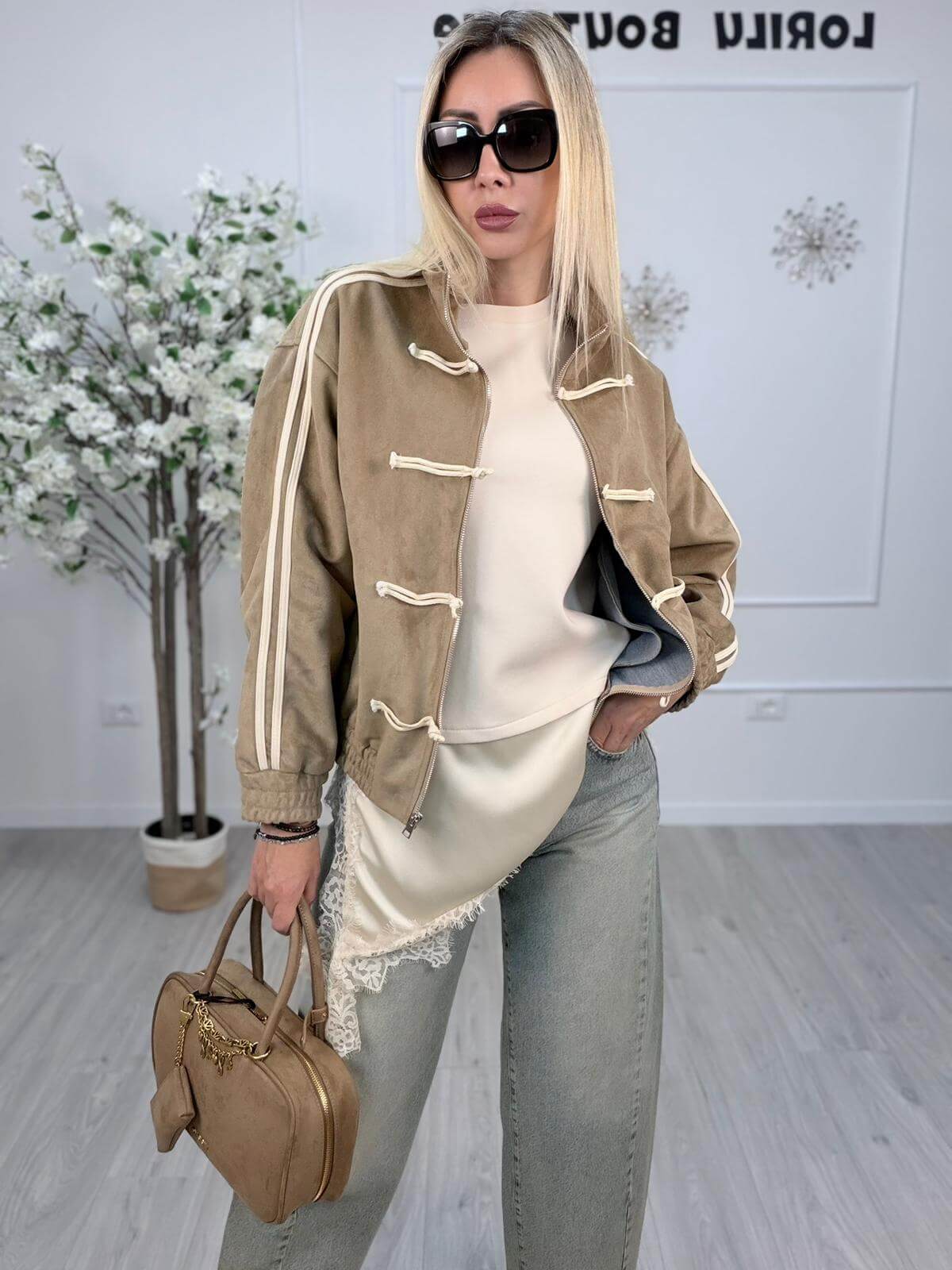 Giacchetto Souvenir color sabbia indossato da una donna in occhiali da sole eleganti e borsa beige.