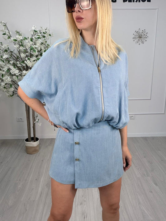 Giacca lyocell denim chiaro con zip, maniche ampie e bottoni laterali indossata da modella in ambientazione moderna.