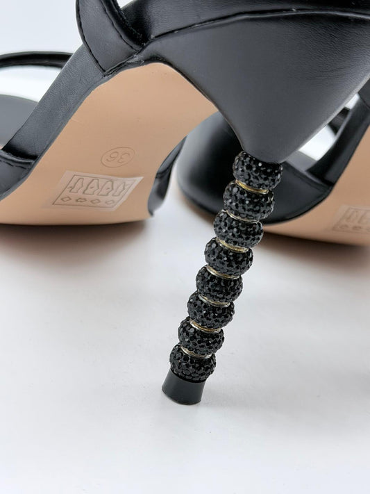 Dettaglio dei sandali tacco gioiello neri Divine Follie con strass luminosi sul tacco.