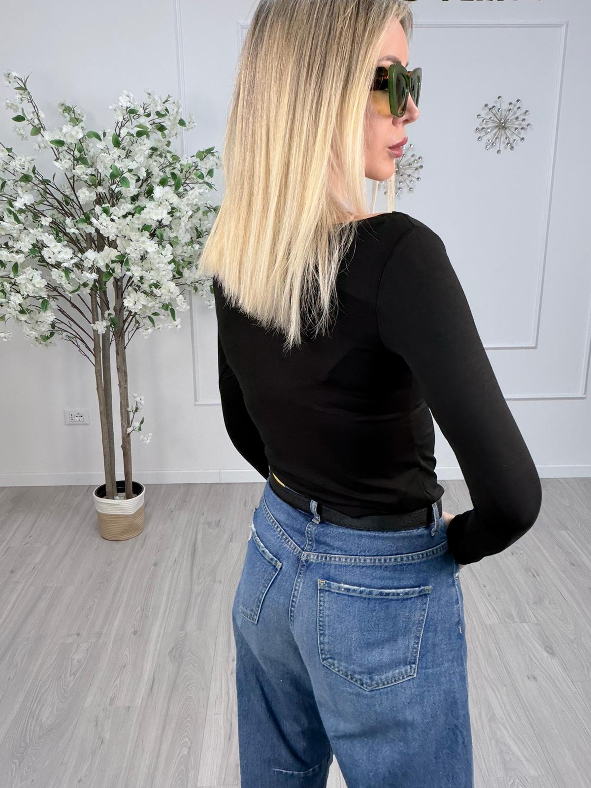 Model wearing a black long-sleeve top and blue jeans, showcasing a stylish back view with sunglasses.